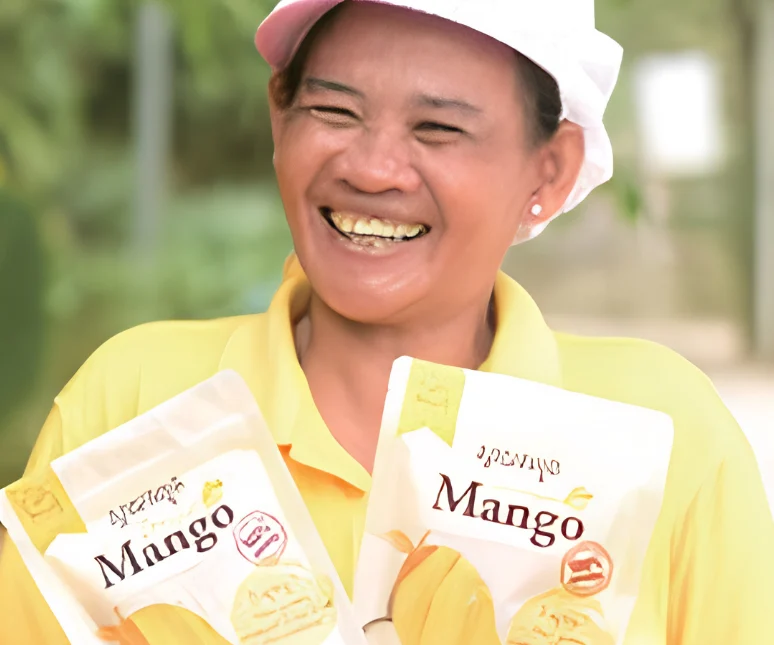 A Hesed farmer partner holding packs of dried Keo Romeat mango